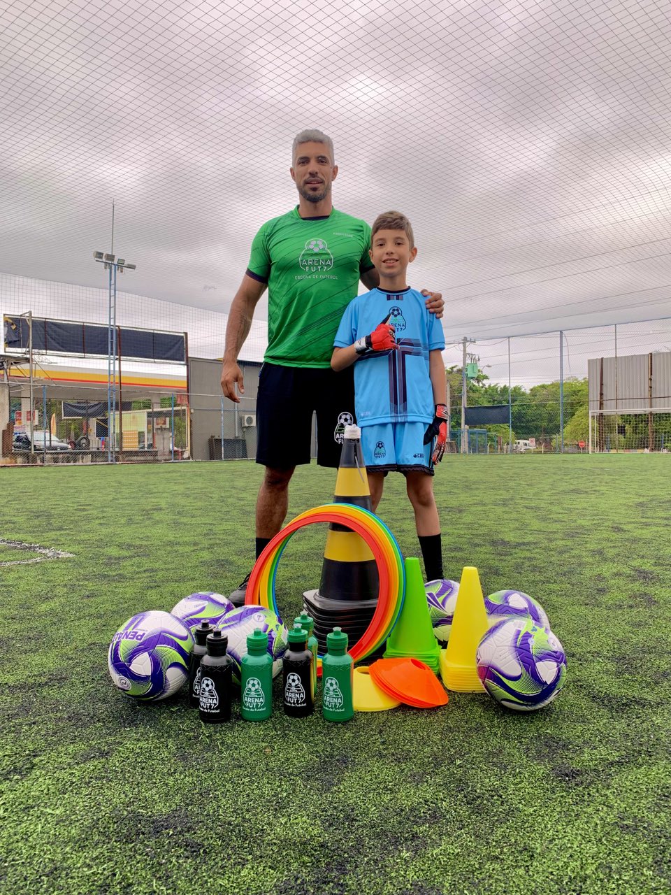 Professor e aluno da Arena Fut7 com bolas e equipamentos de treino